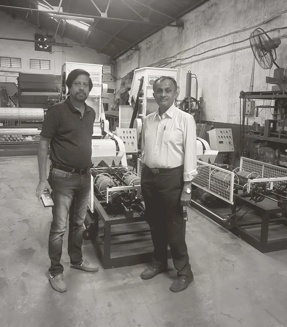 Both founders of 2M Engineers on the shop floor beside a coir spinning machine